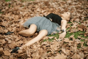 una mujer tirada en las hojas del bosque