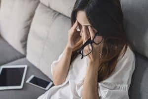 mujer con las gafas en la mano y tapándose los ojos