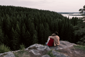 pareja sentada en una piedra viendo el bosque